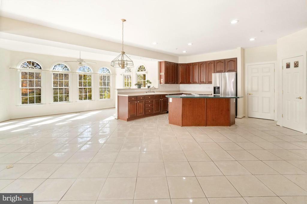 Kitchen with a large island, dark wood cabinets, stainless steel refrigerator, and arched windows.