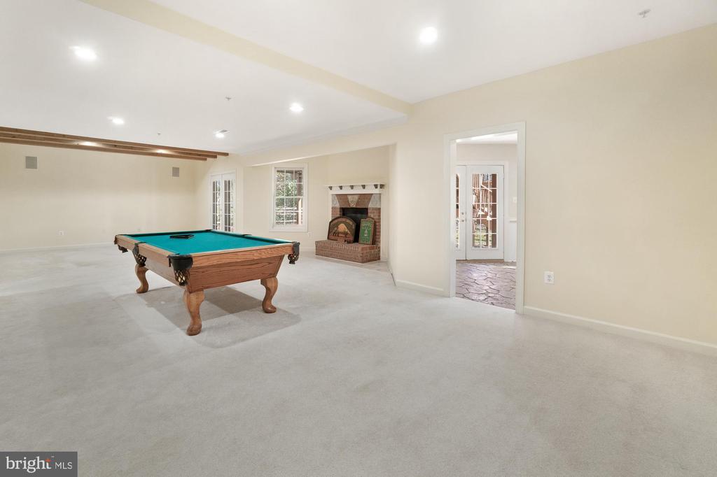 Carpeted recreation room with a pool table and brick fireplace.