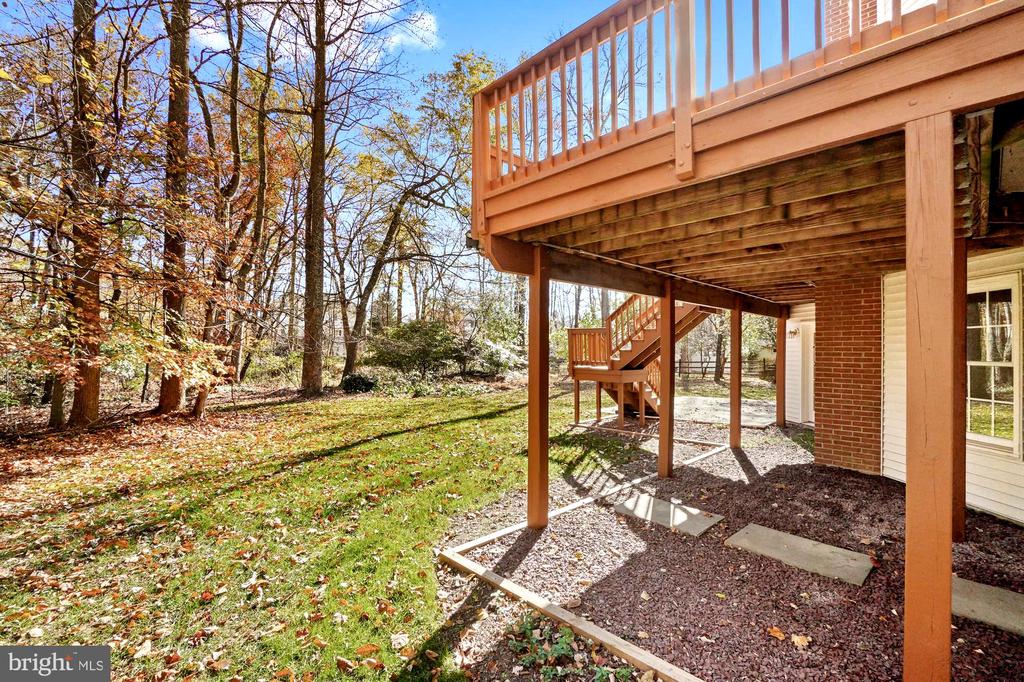 Elevated wooden deck and stairs overlooking a wooded backyard.