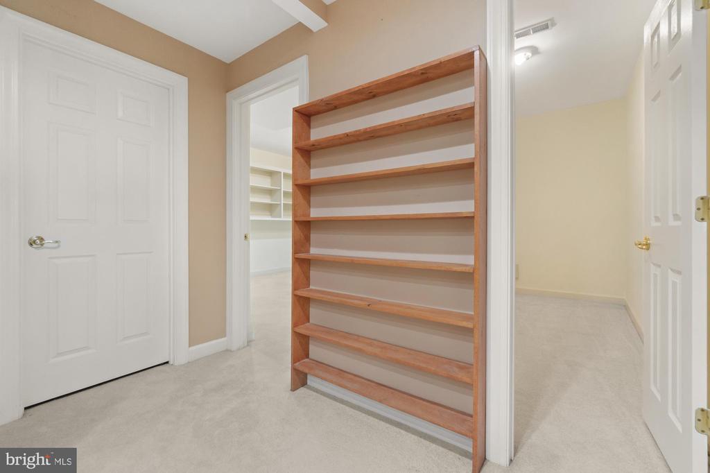 Carpeted interior with a tall built-in wooden shelving unit between two doorways.