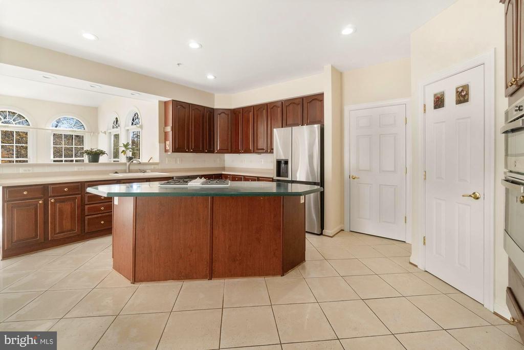 Kitchen with dark wood cabinets, a large island, stainless steel appliances, and arched windows above the sink.