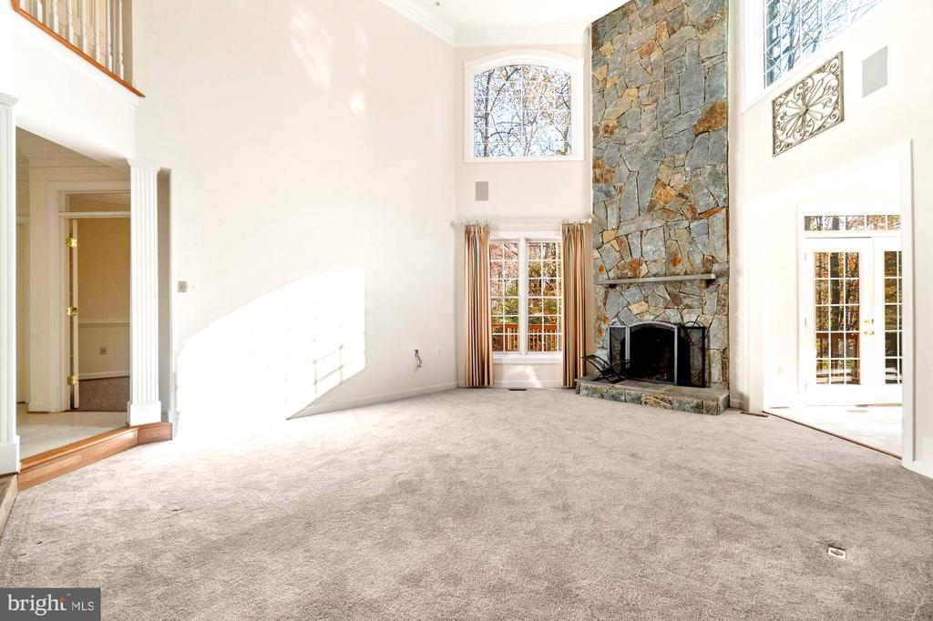 Living room with a floor-to-ceiling stone fireplace, vaulted ceiling, and large windows.