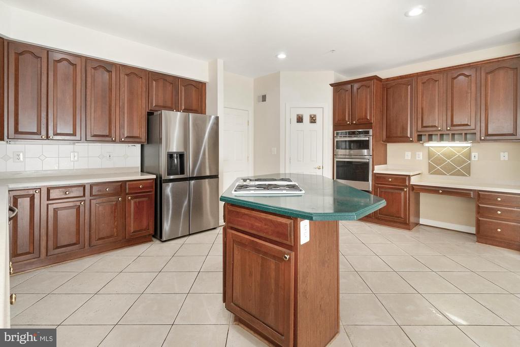 Kitchen with dark wood cabinets, a green-topped island, and stainless steel appliances.