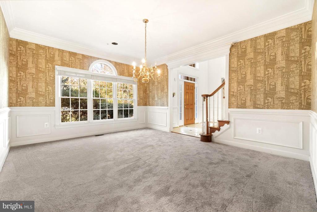Empty dining room with patterned wallpaper, a chandelier, and a large divided-light window.