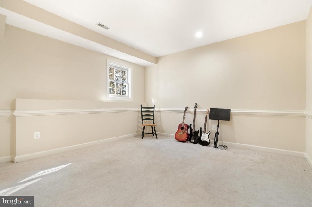 Carpeted room with a small window, black chair, and three guitars.