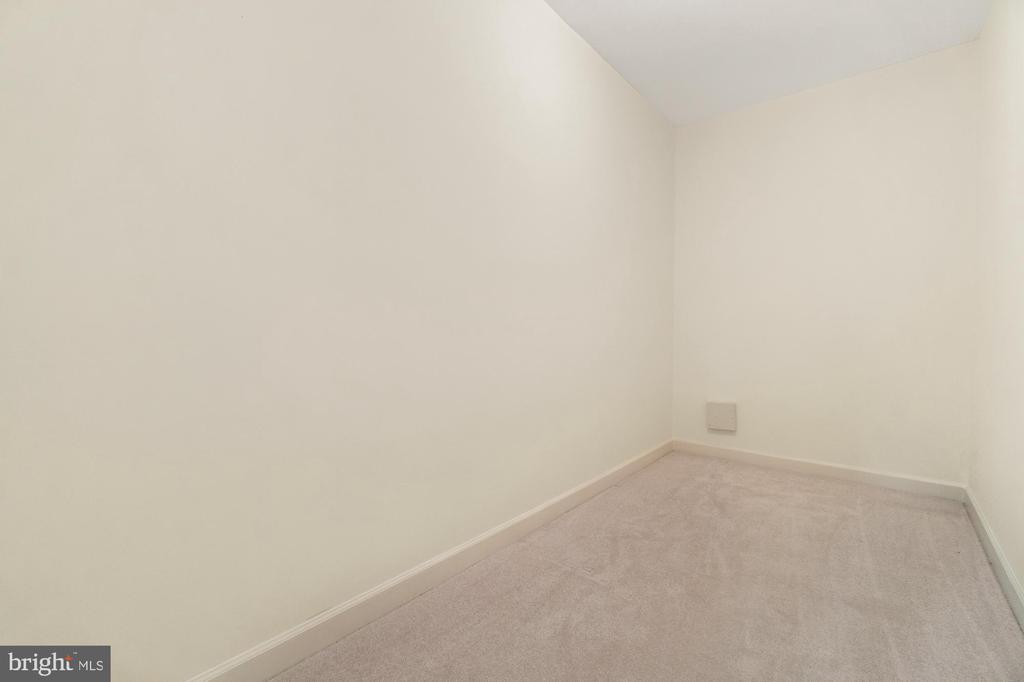 Empty carpeted room with cream walls and a low wall vent.