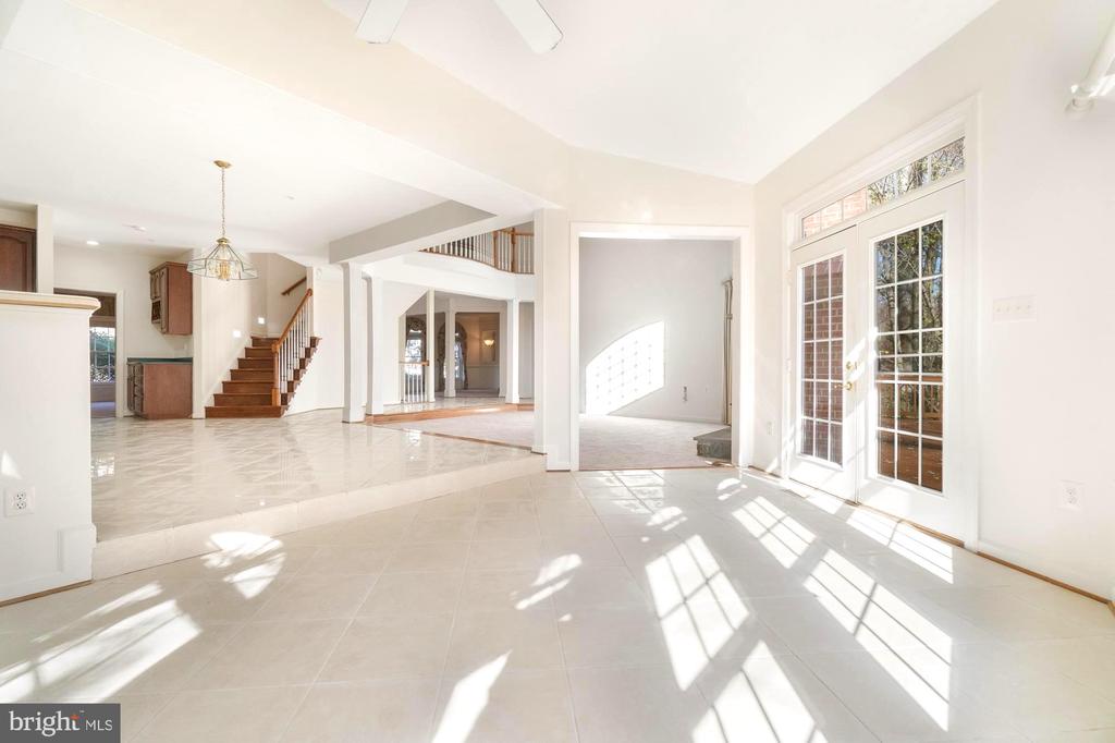 Bright tiled foyer with French doors, opening toward the kitchen and staircase.