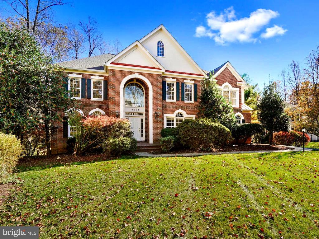 Two-story brick house with white gables, an arched entry, and a broad front lawn.