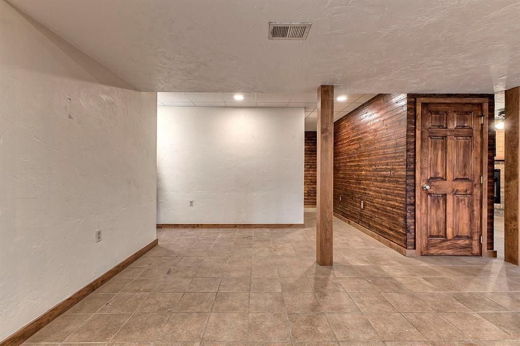 Finished basement with tiled floors, a wood support column, and a dark wood accent wall.