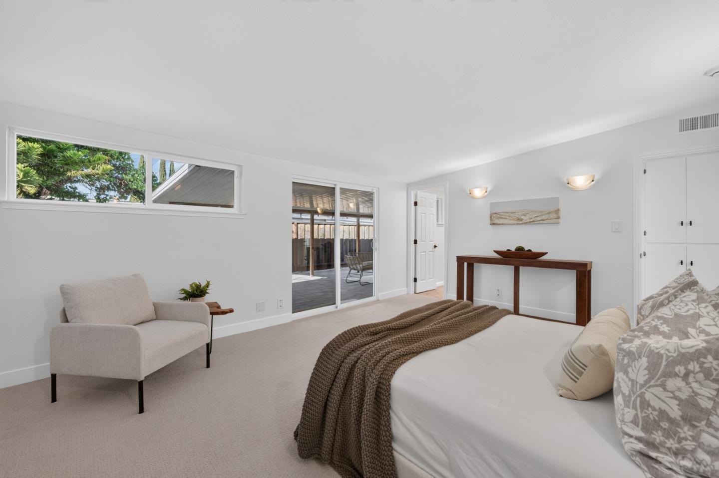 Furnished bedroom with a large bed and sliding glass doors to a covered patio.