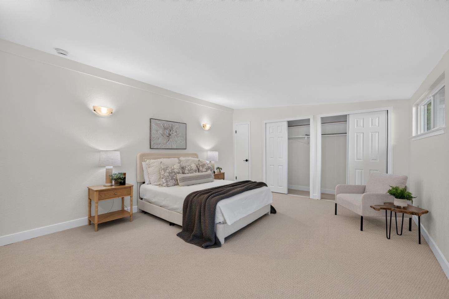 Staged bedroom with a large bed, open closets, and a sitting area.