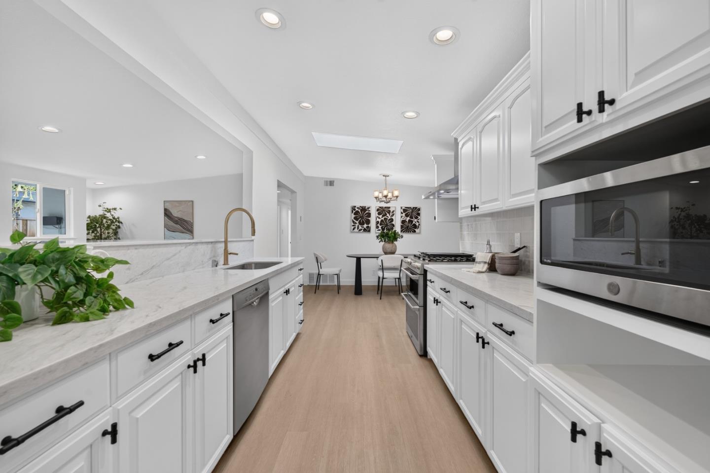 Remodeled white kitchen with marble-look counters, stainless steel appliances, and a dining nook.
