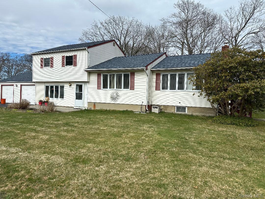 White two-story house with red shutters, an attached garage, and a broad front lawn.