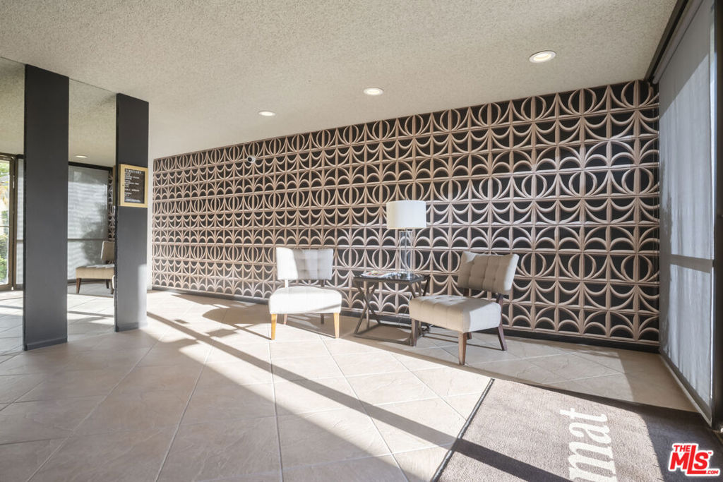 Condo lobby seating with two upholstered chairs against a geometric patterned wall.