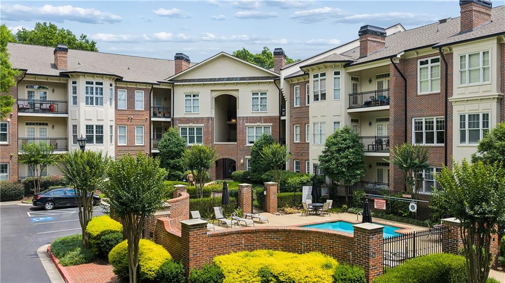 Brick apartment building around a landscaped courtyard with a swimming pool and patio seating.