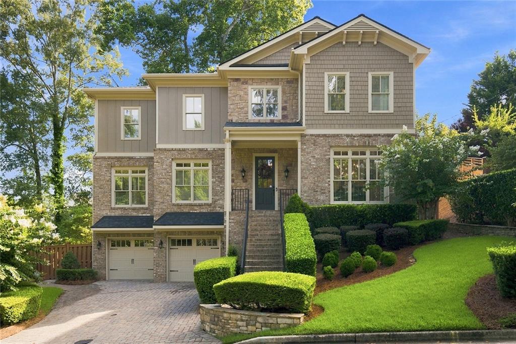 Two-story brick and gray-sided home with a covered entry, double garage, and landscaped lawn.
