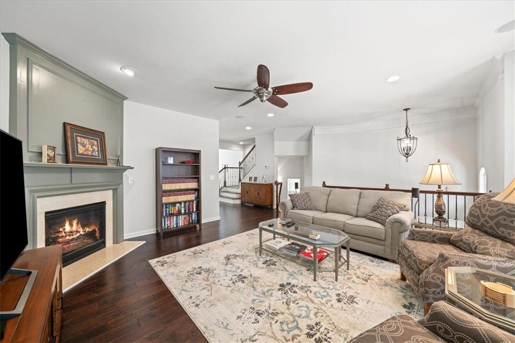 Living room with a lit fireplace, dark hardwood floors, and a patterned rug.