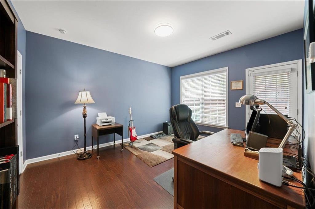 Furnished home office with blue walls, a large wooden desk, and a red electric guitar.