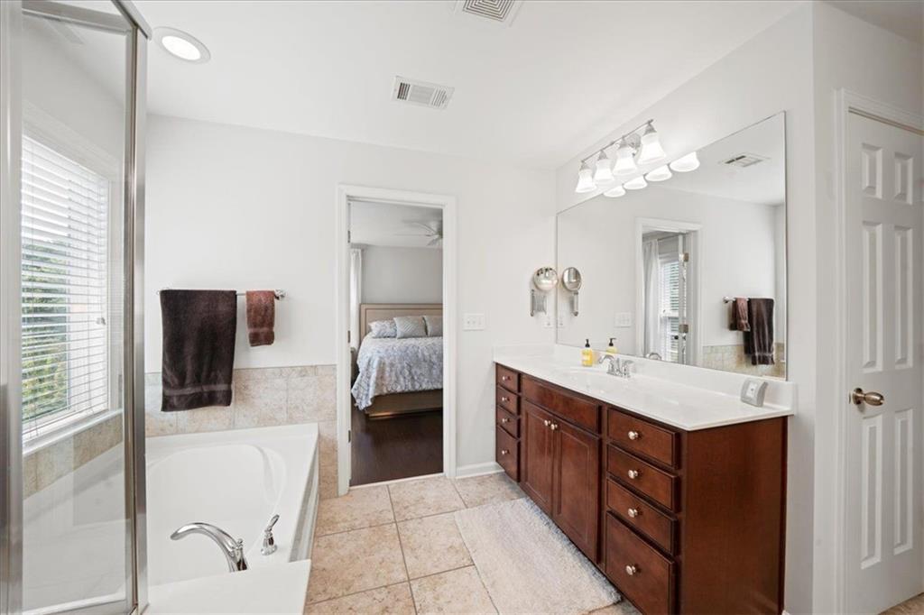 Bathroom with a glass-enclosed tub and dark wood double vanity beside an open bedroom doorway.