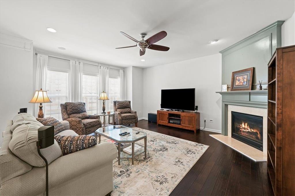 Living room with a green-mantled fireplace, dark hardwood floors, and tall windows.