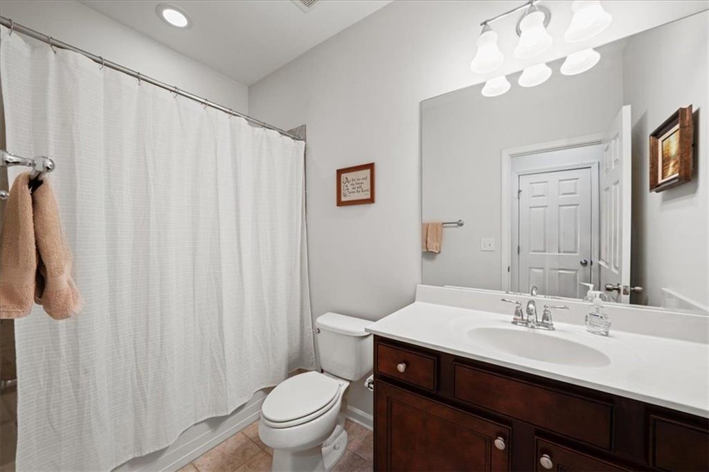 Bathroom with a white shower curtain, large mirror, and dark wood vanity.