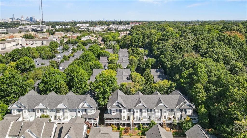 Aerial view of townhomes among dense trees, with the Atlanta skyline in the distance.