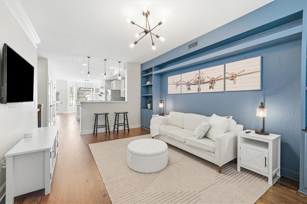 Living room with a white sofa against a blue built-in wall and an open kitchen beyond.