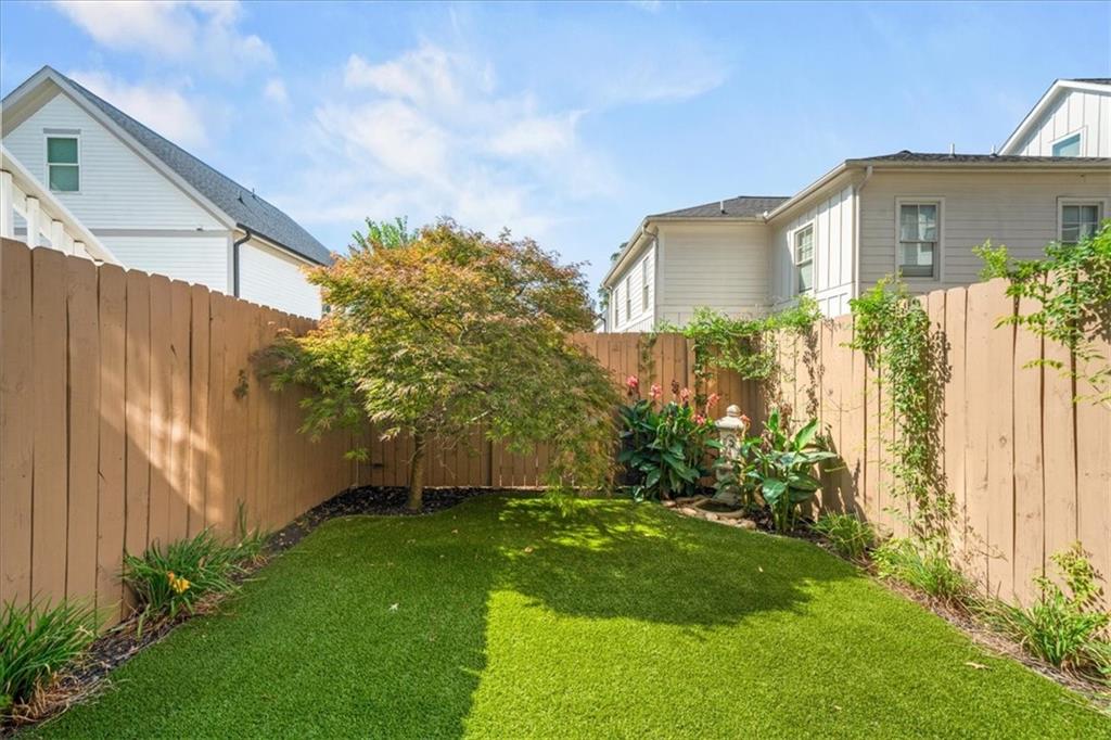 Fenced backyard with a lawn, Japanese maple, and planted garden beds.