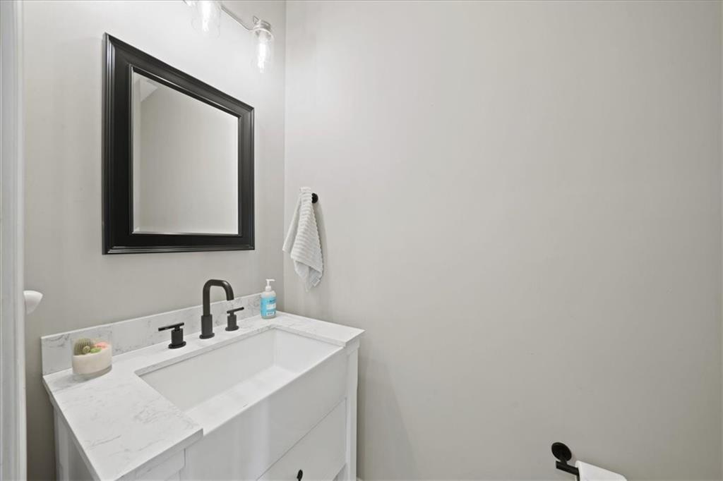 Bathroom vanity with a white marble-look counter, black fixtures, and a black-framed mirror.