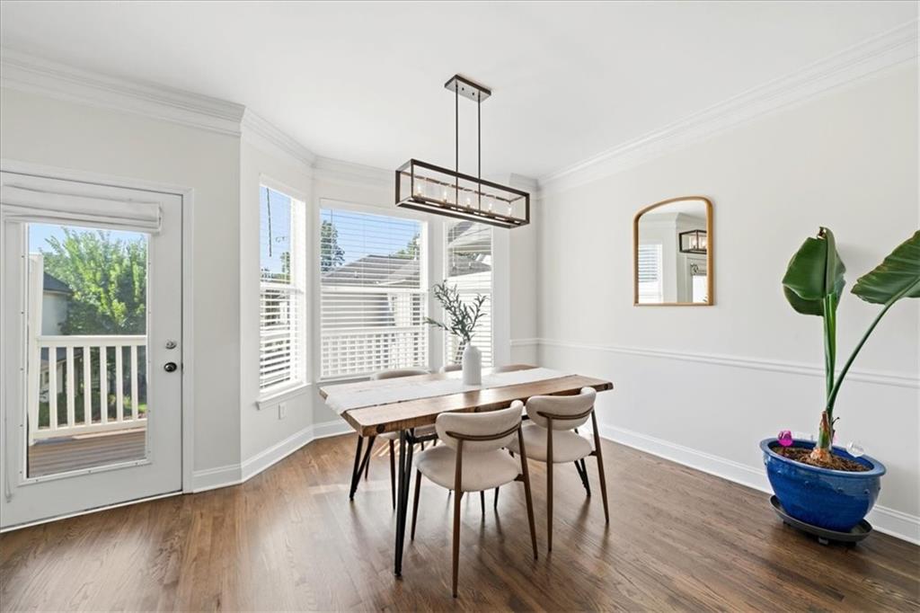 Dining room with a wood table, bay windows, and a glass door to the balcony.