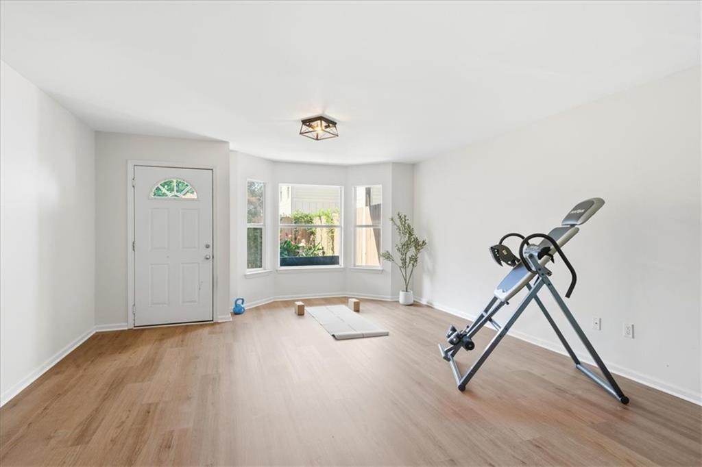 Exercise room with a yoga mat and inversion table beside a bright bay window.