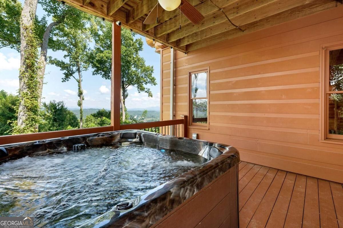 Hot tub on a covered wooden deck overlooking wooded mountains.
