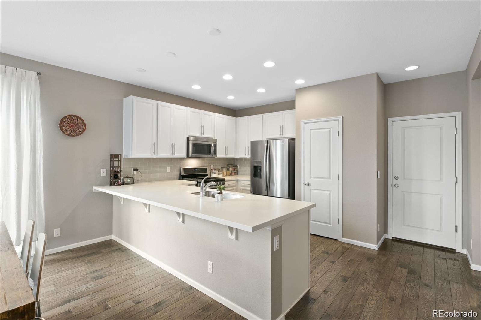 Modern kitchen with white cabinets, stainless appliances, and a long peninsula sink.