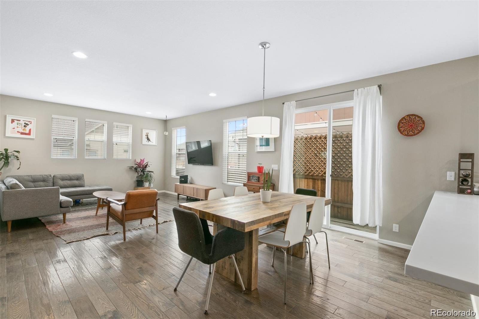 Open-plan living and dining room with a wood table, gray sectional, and sliding glass doors to a patio.