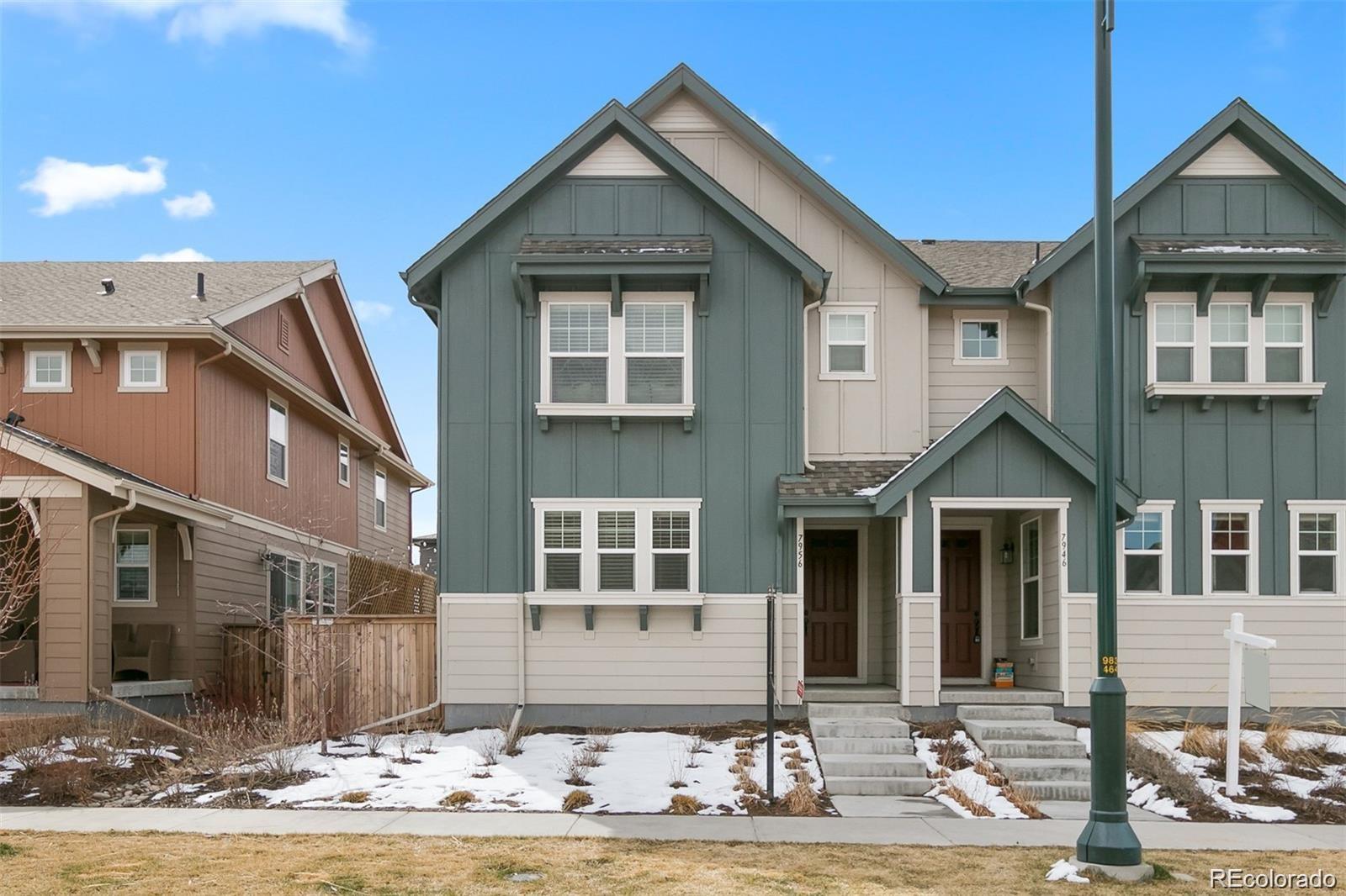 Attached blue-green and beige townhomes with steep gabled roofs and snow-patched front yards.