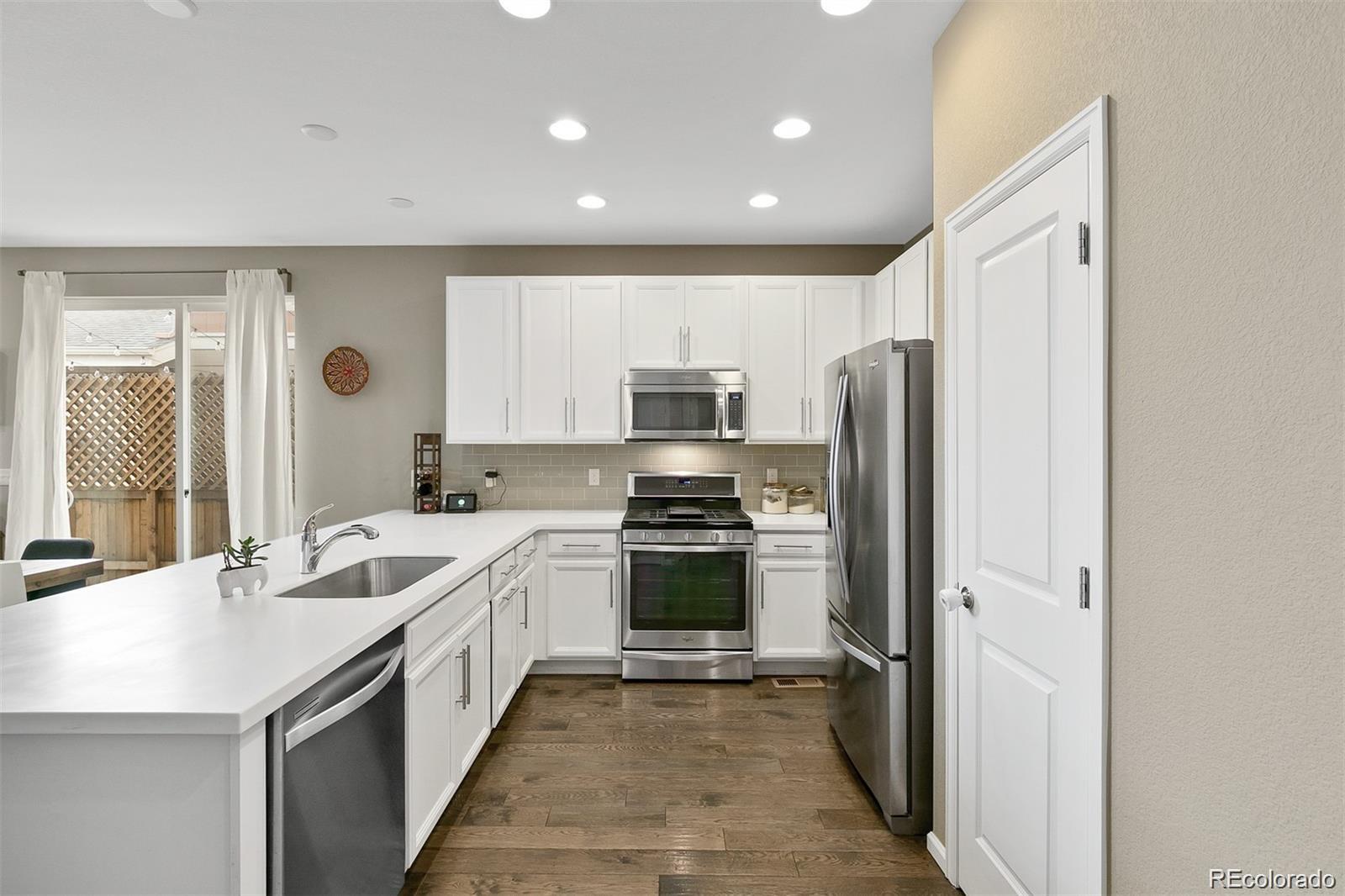 Kitchen with white shaker cabinets, stainless steel appliances, and a peninsula beside sliding patio doors.