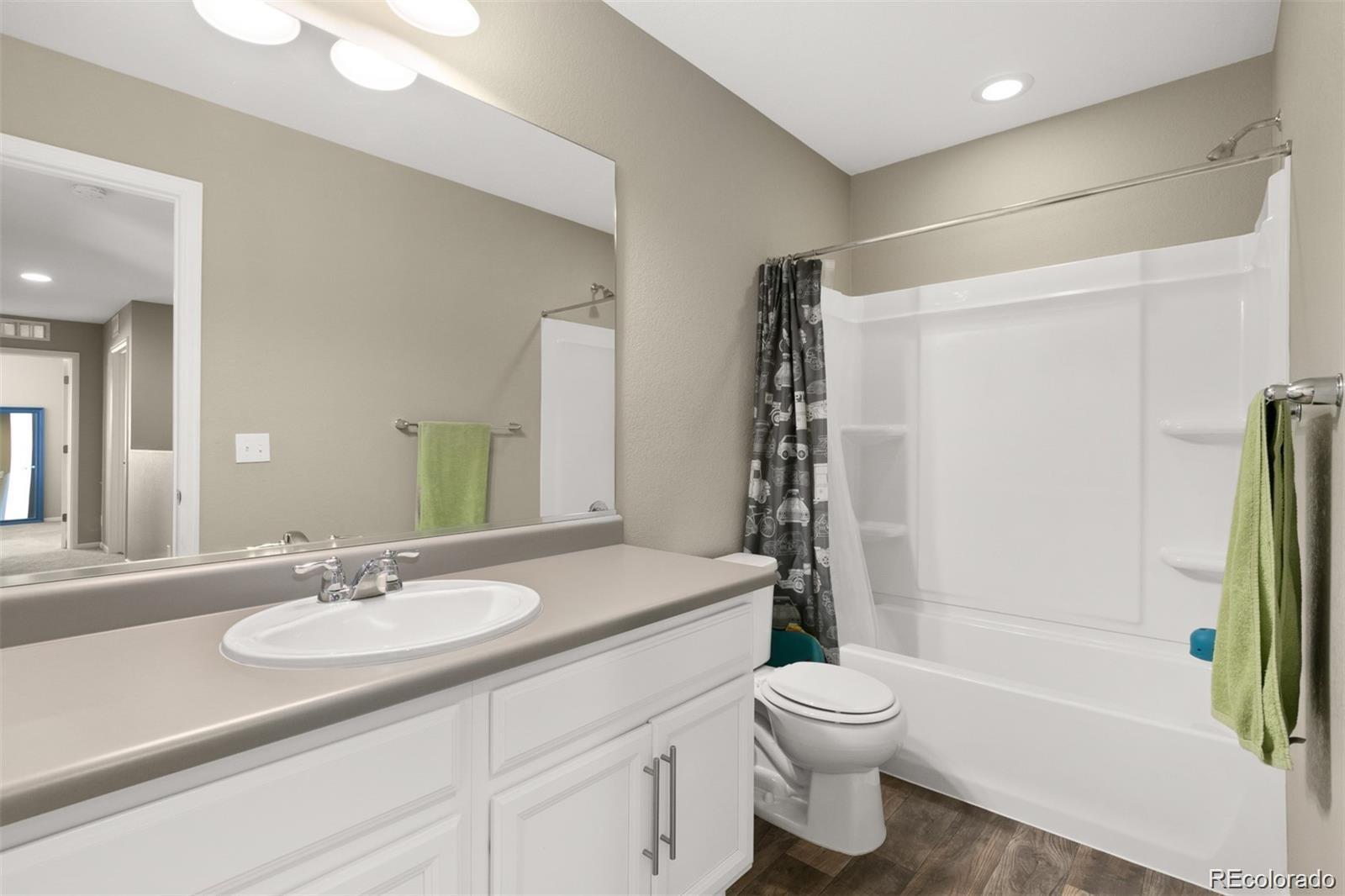 Bathroom with a white vanity, large mirror, and tub-shower.
