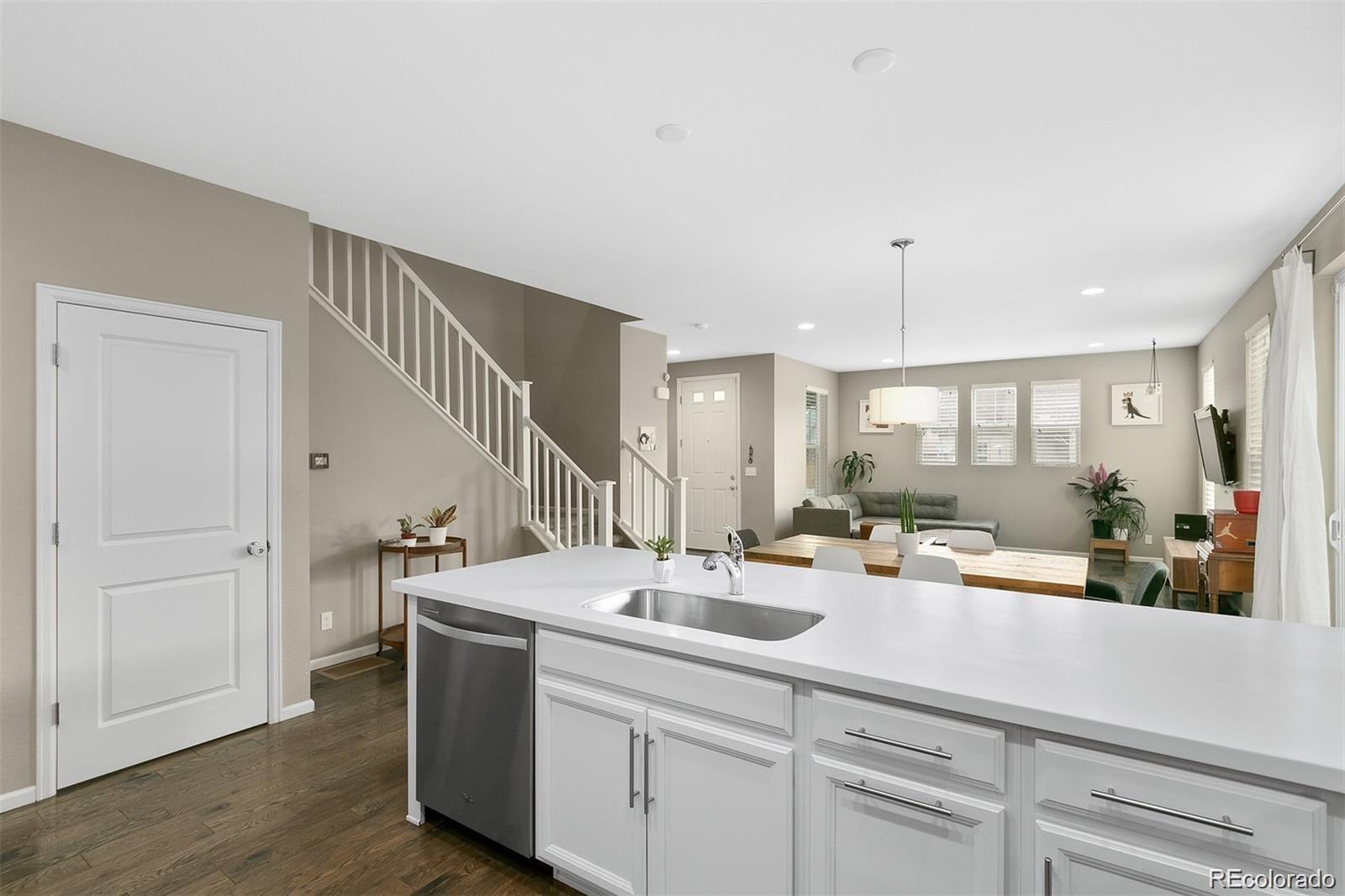 Open-plan kitchen with a large white island, staircase, dining area, and living room.