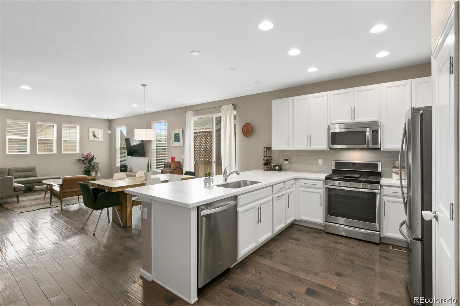 Open-plan kitchen with a large white island, stainless steel appliances, and dining and living areas beyond.