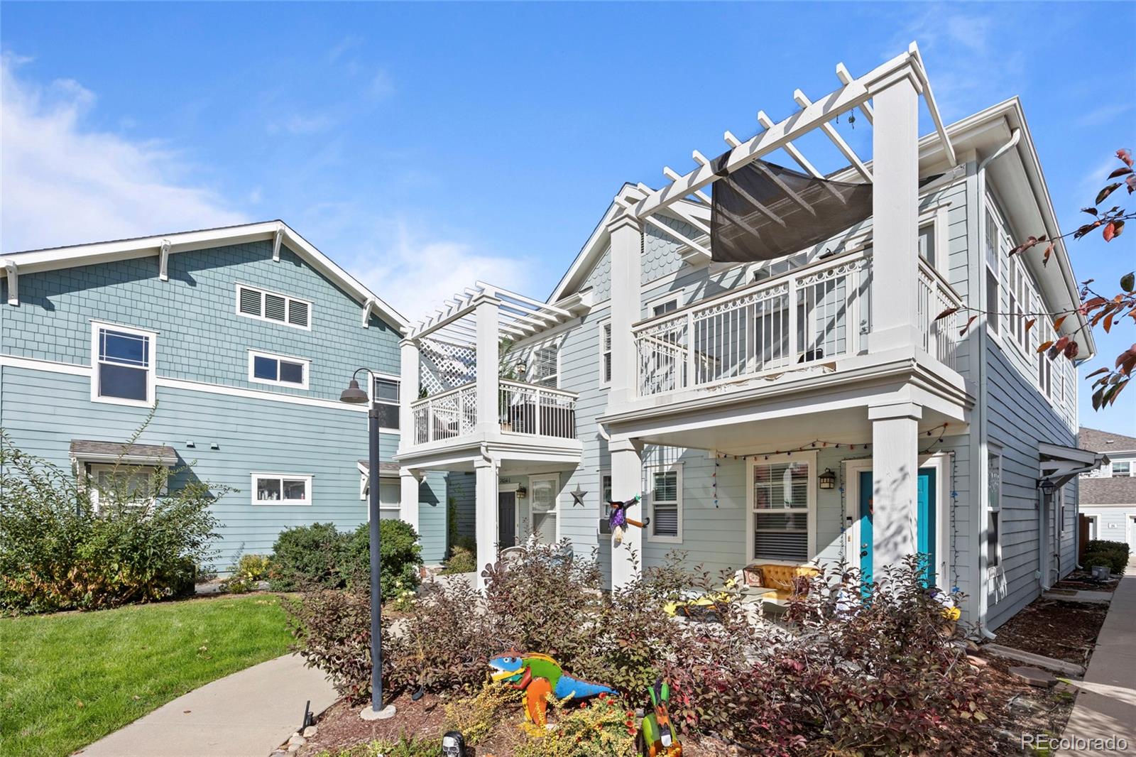 Light blue townhouse with raised pergola-covered balconies and a landscaped courtyard.