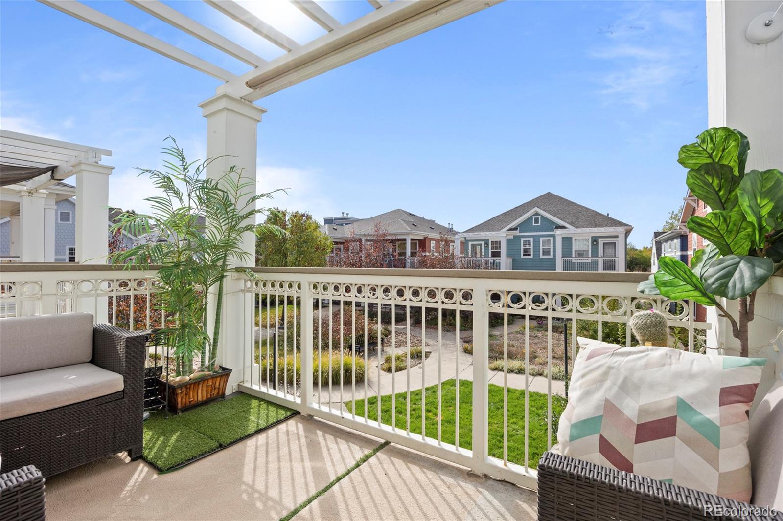 Furnished patio with pergola, potted plants, and views over a landscaped courtyard.