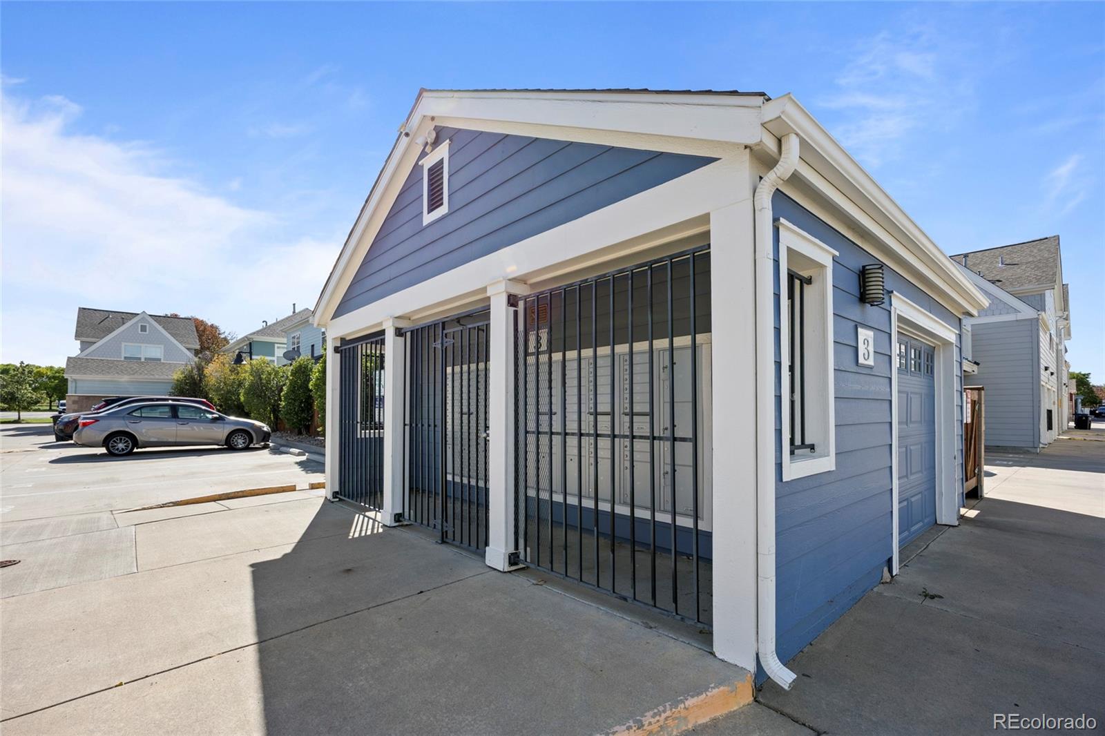 Blue-sided unit 3 with white trim, a barred entrance, and a garage door.