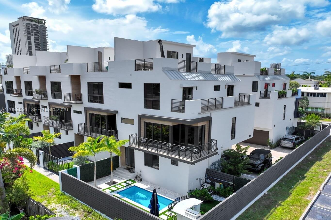 Modern white residences with rooftop terraces and a courtyard swimming pool, viewed from above.