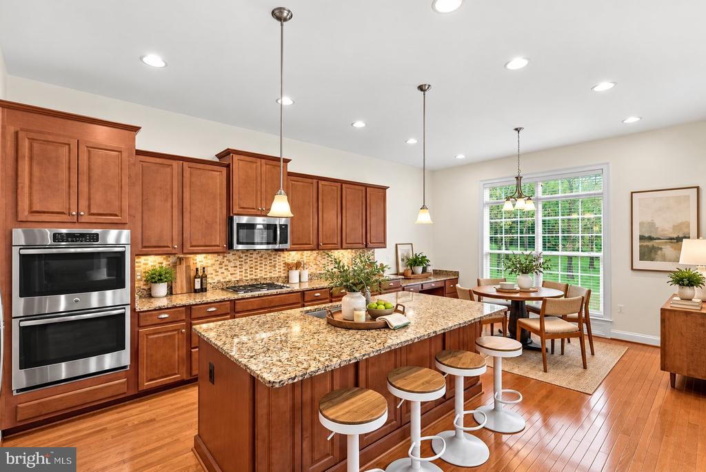 Kitchen with cherry cabinets, granite island, stainless double ovens, and a breakfast dining area.