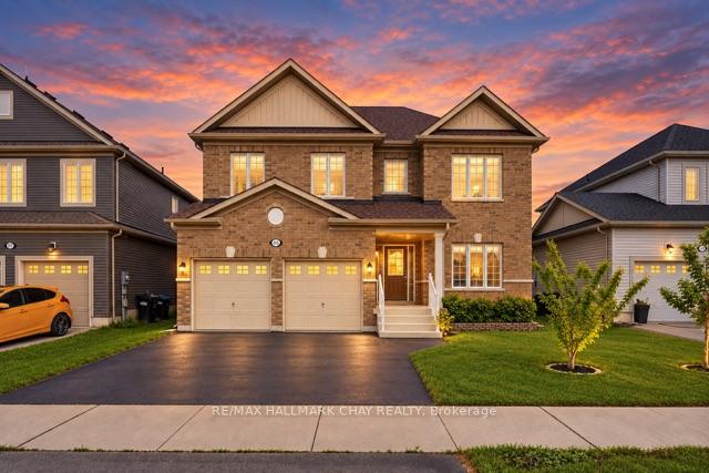Two-story brick house with a double garage and landscaped lawn beneath a vivid sunset sky.