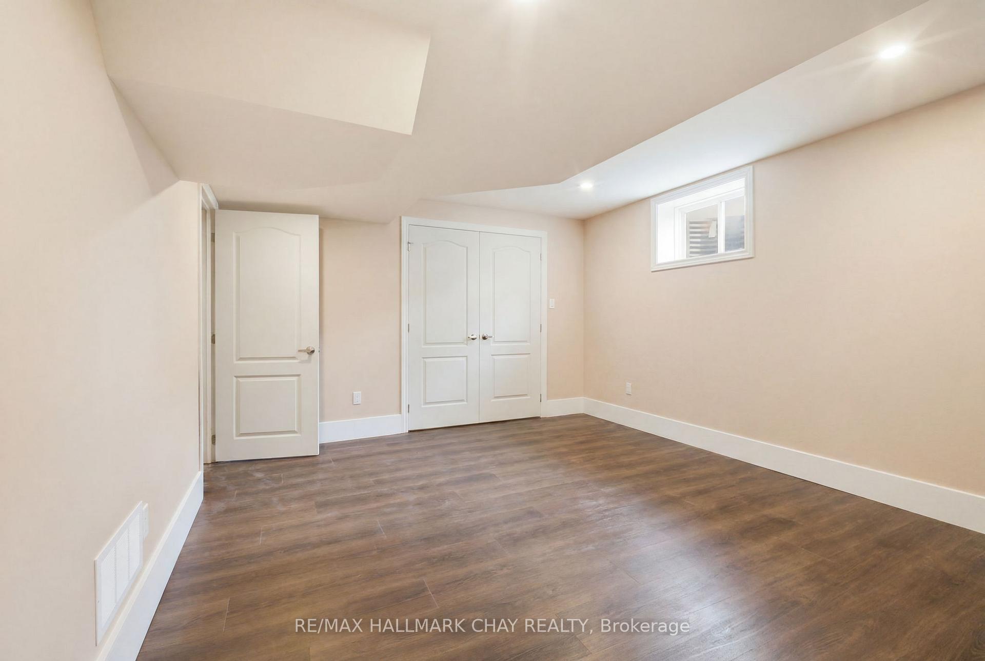 Empty room with a vaulted ceiling, double closet doors, and dark wood-look flooring.