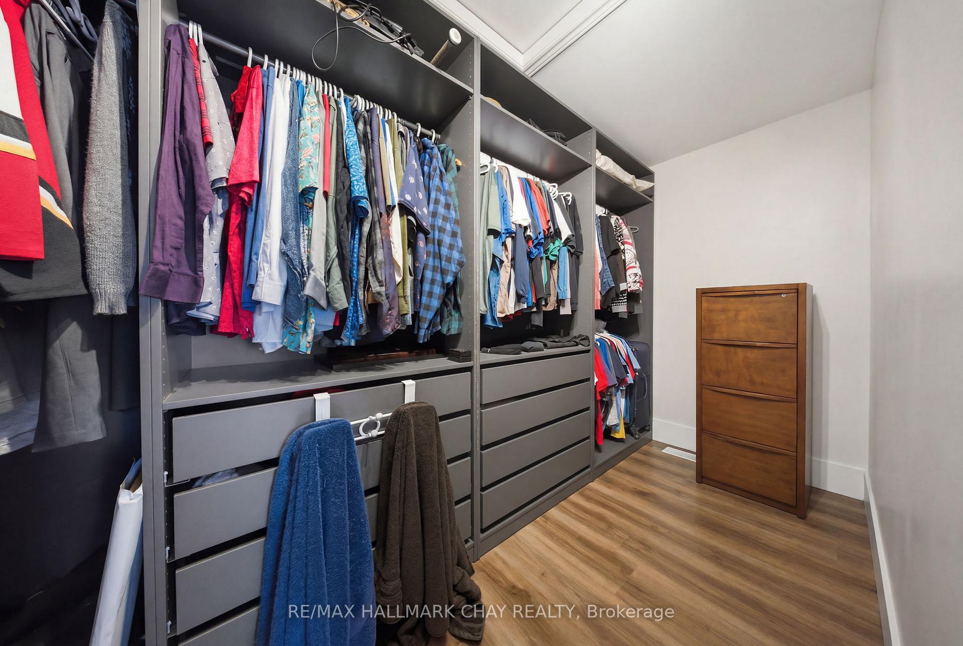 Walk-in closet with extensive built-in clothing storage, drawers, and wood-look flooring.