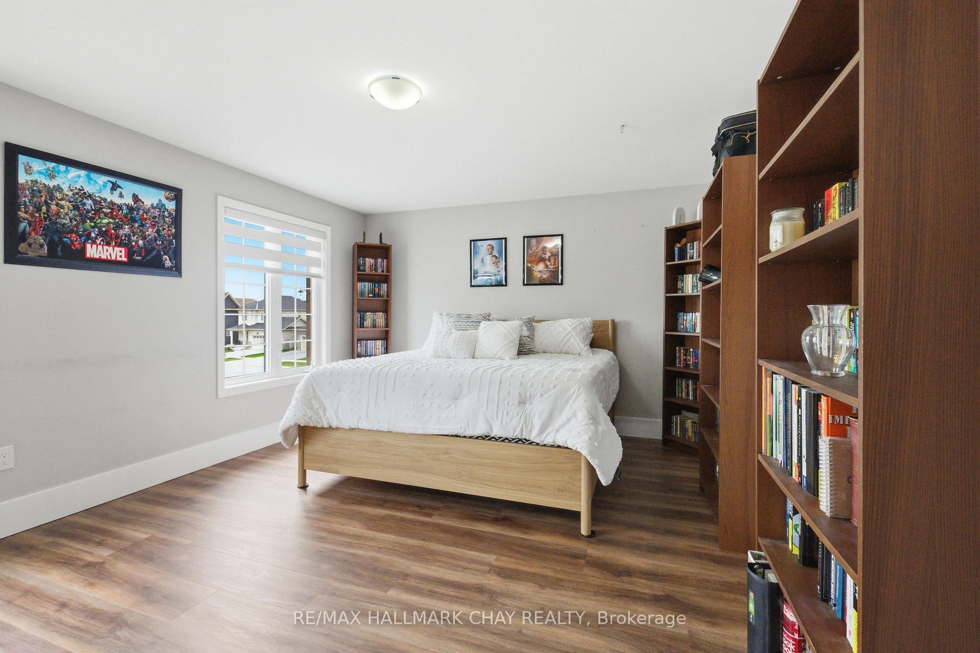 Bedroom with a white bed, wood-look flooring, and tall bookcases along the right wall.