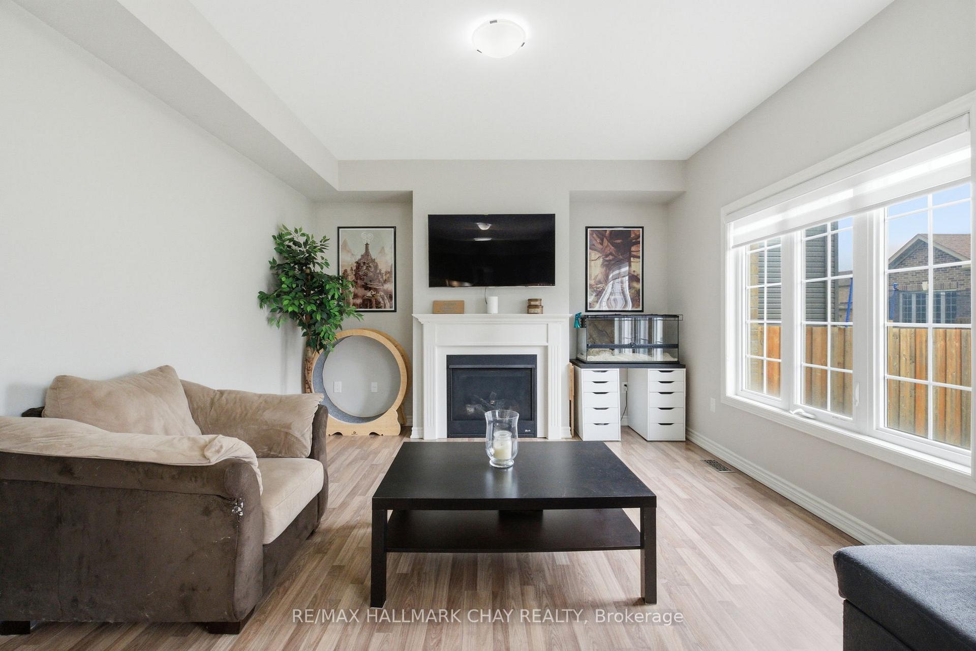 Living room with a fireplace, wall-mounted TV, beige sectional, and large bright window.