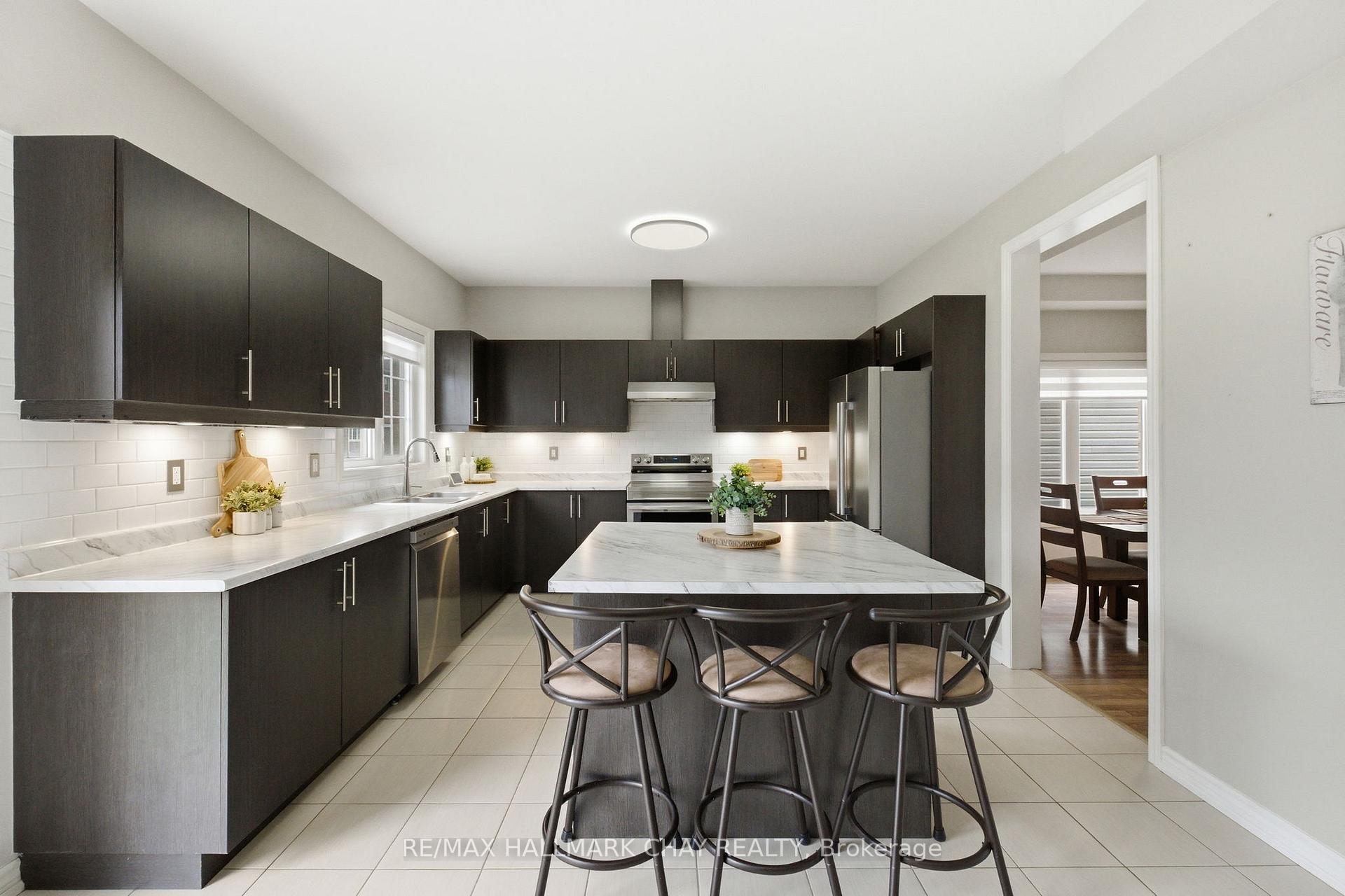 Kitchen with dark cabinets, white counters, stainless appliances, and a large island with stools.